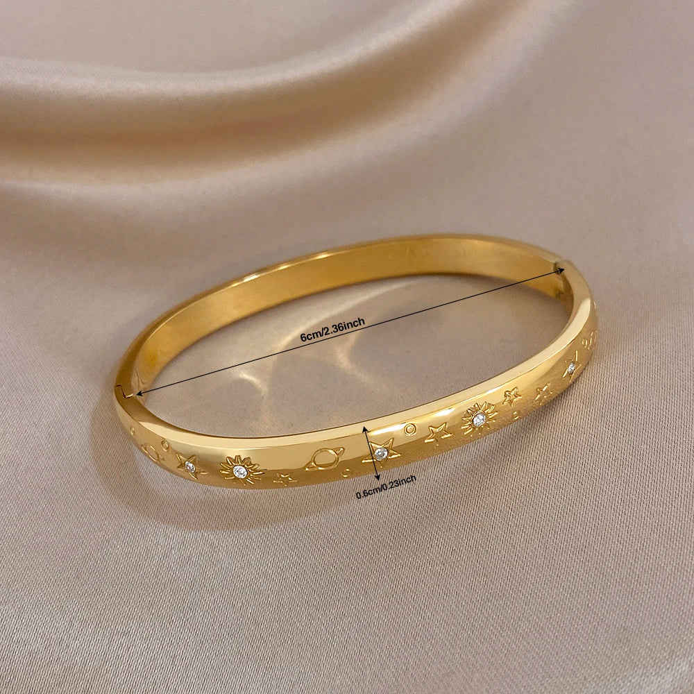 Gold-tone wide cuff bangle with star pattern and tiny crystal-like accents