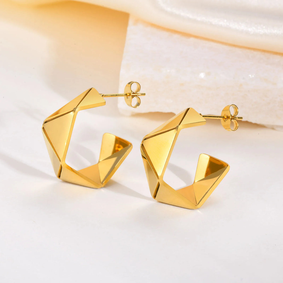 Close-up of gold-plated geometric hoop earrings with secure stud posts