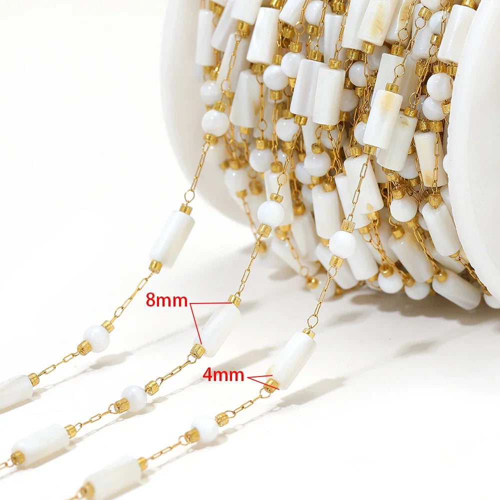 Close-up strand of white shell-style beads with gold links and size reference markings