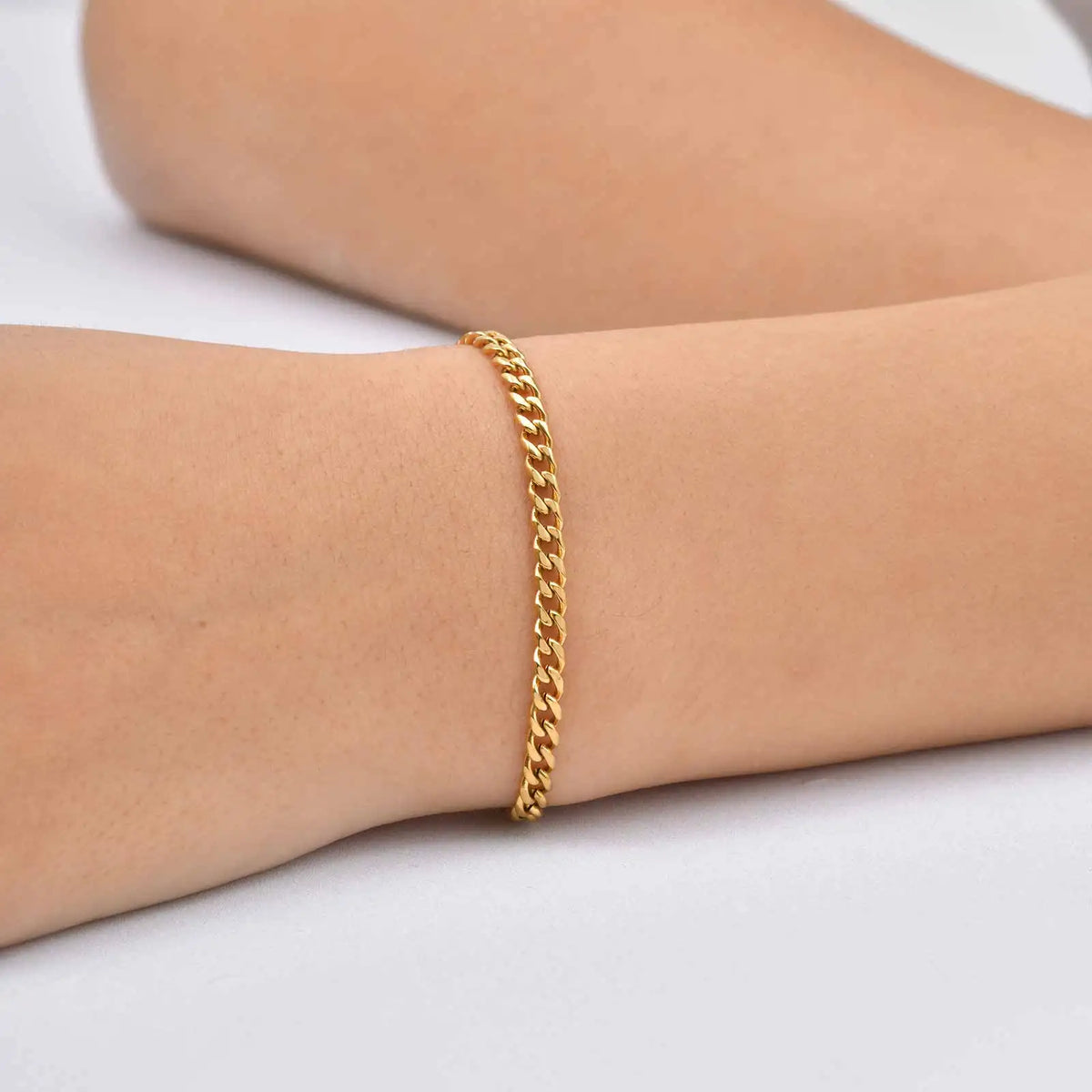 Gold tone curb-link chain bracelet on wrist with close, thin profile