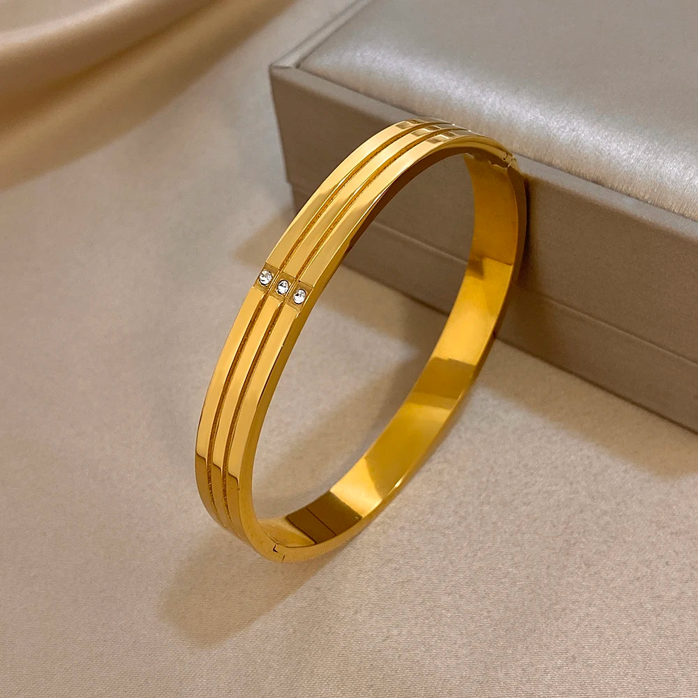 Gold-tone stainless steel hinged cuff bangle with crystal line accent