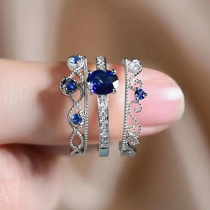 Three-piece silver-tone CZ rings with blue stones and ornate heart motif bands