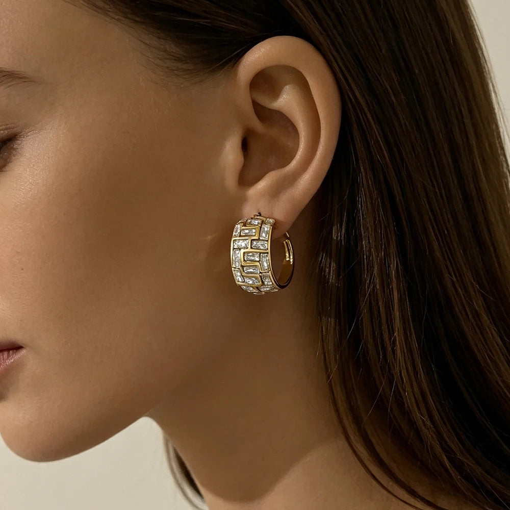 Gold geometric hoop earring with clear square-cut stones, worn on an ear