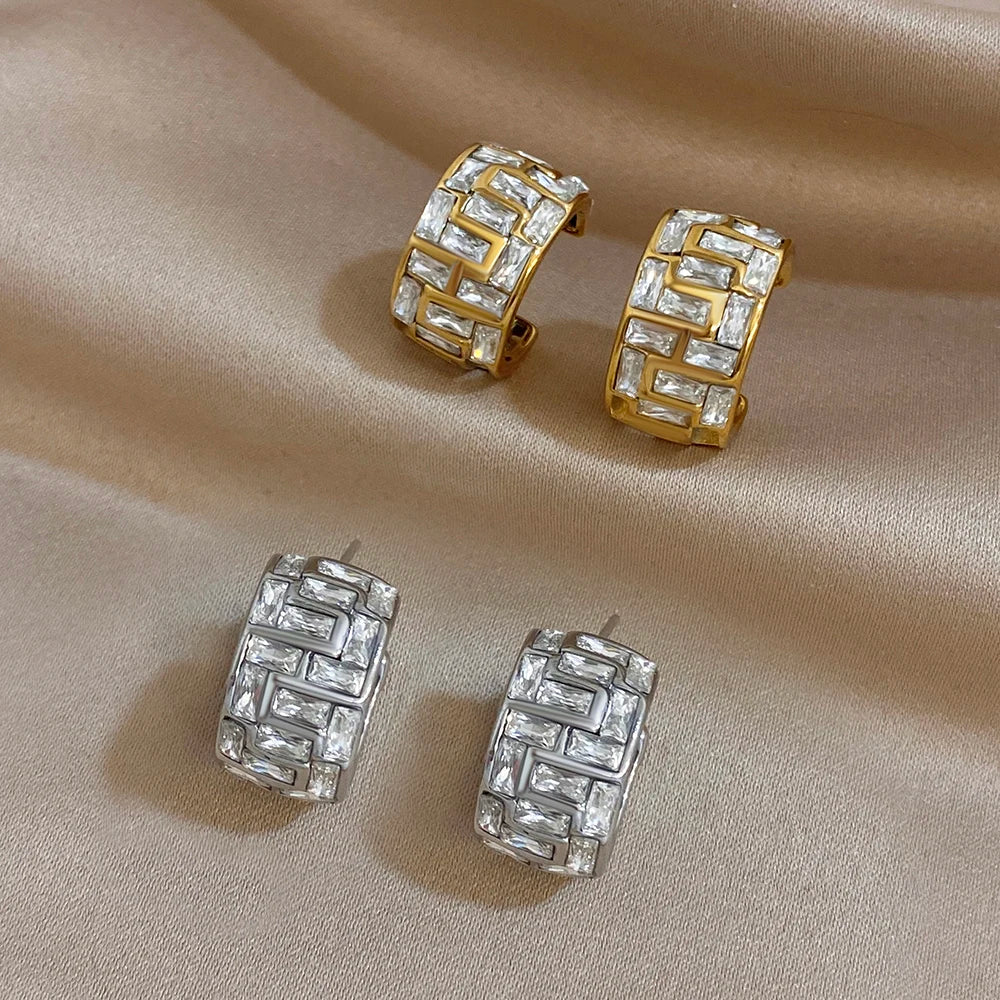 Pairs of gold and silver geometric hoop earrings with clear stones