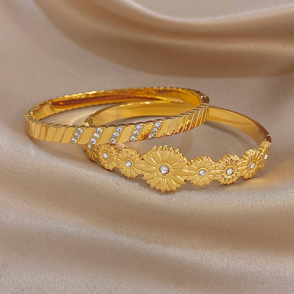 Pair of gold tone cuff bangles with floral design and clear rhinestone details
