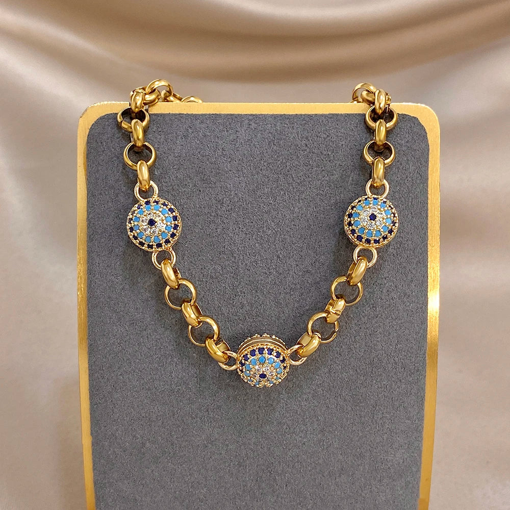 Gold-tone chain bracelet with blue evil-eye round charms on display stand