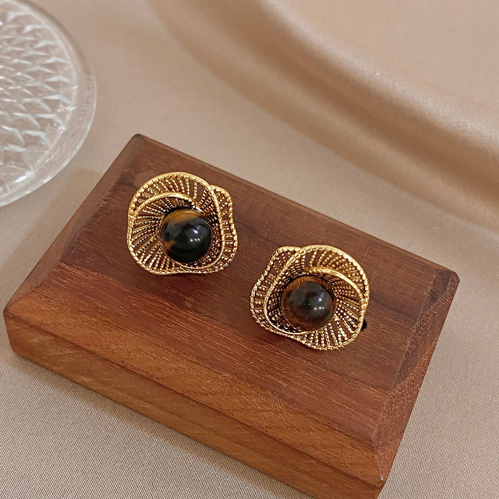 Gold-tone flower stud earrings with dark round stone and ornate border detail
