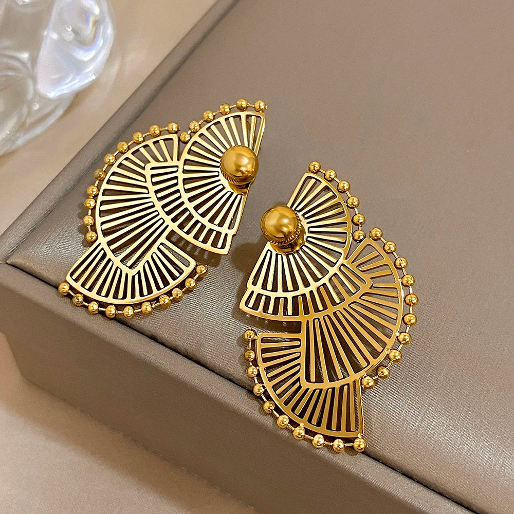 Gold-tone openwork earrings arranged at an angle, with round studs and beaded rims