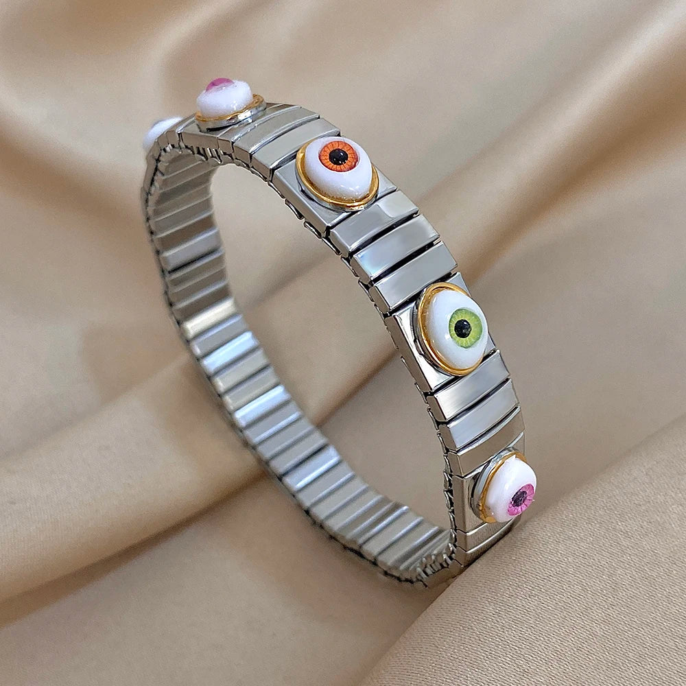 Silver-tone elastic bracelet with glossy evil eye insets in blue, green, orange, and pink