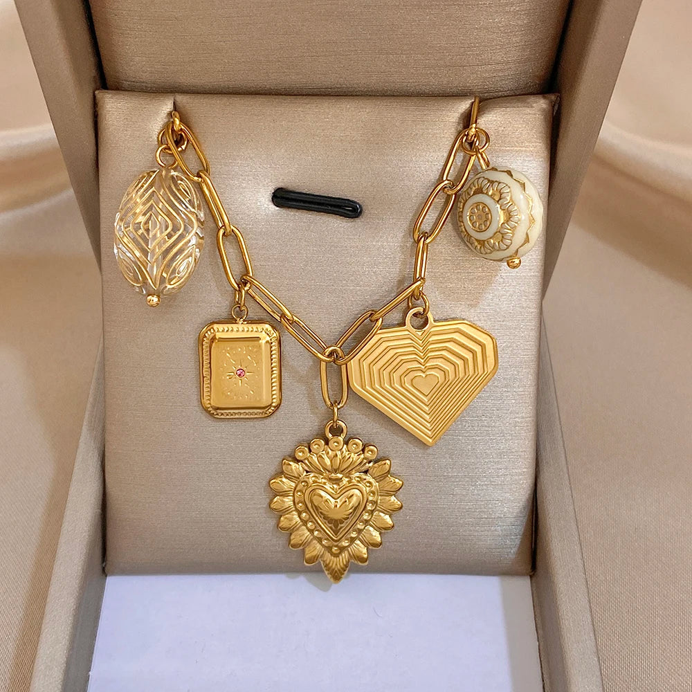 Gold chain necklace with heart charms, geometric shield pendant, and leaf teardrop charm