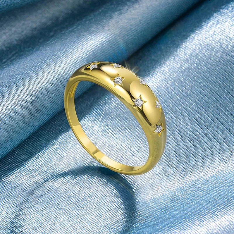 Gold-tone wedding band with star inlays and sparkle stones, on blue fabric