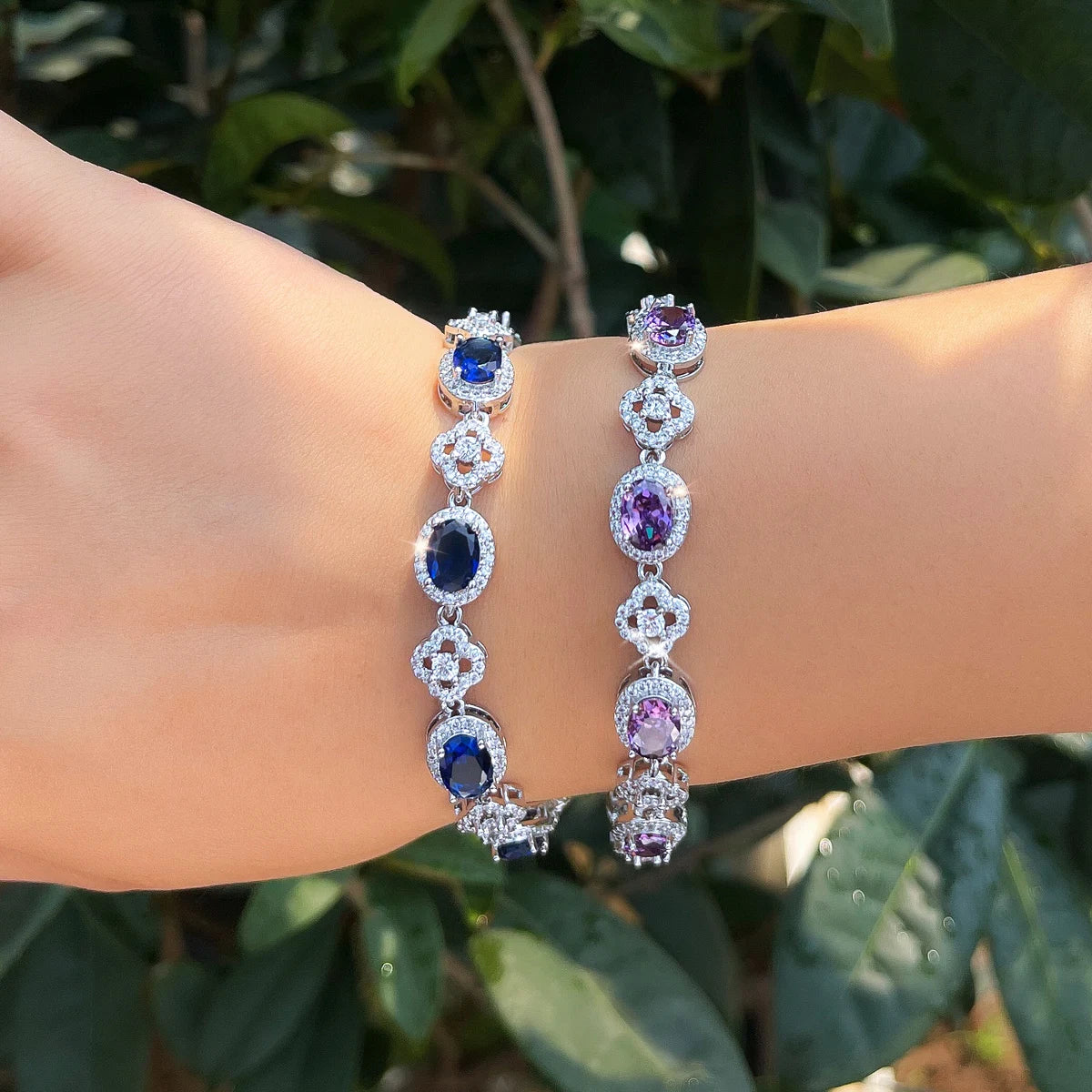 Blue and purple oval crystal flower tennis bracelets worn on a wrist
