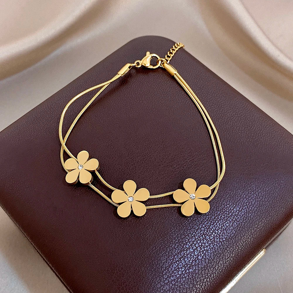 Gold double-layer snake chain bracelet with five flower charms and crystal centers, clasp at top