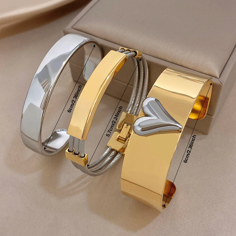 Stacked gold and silver cuff bangles with heart charm and rectangular geometric accents
