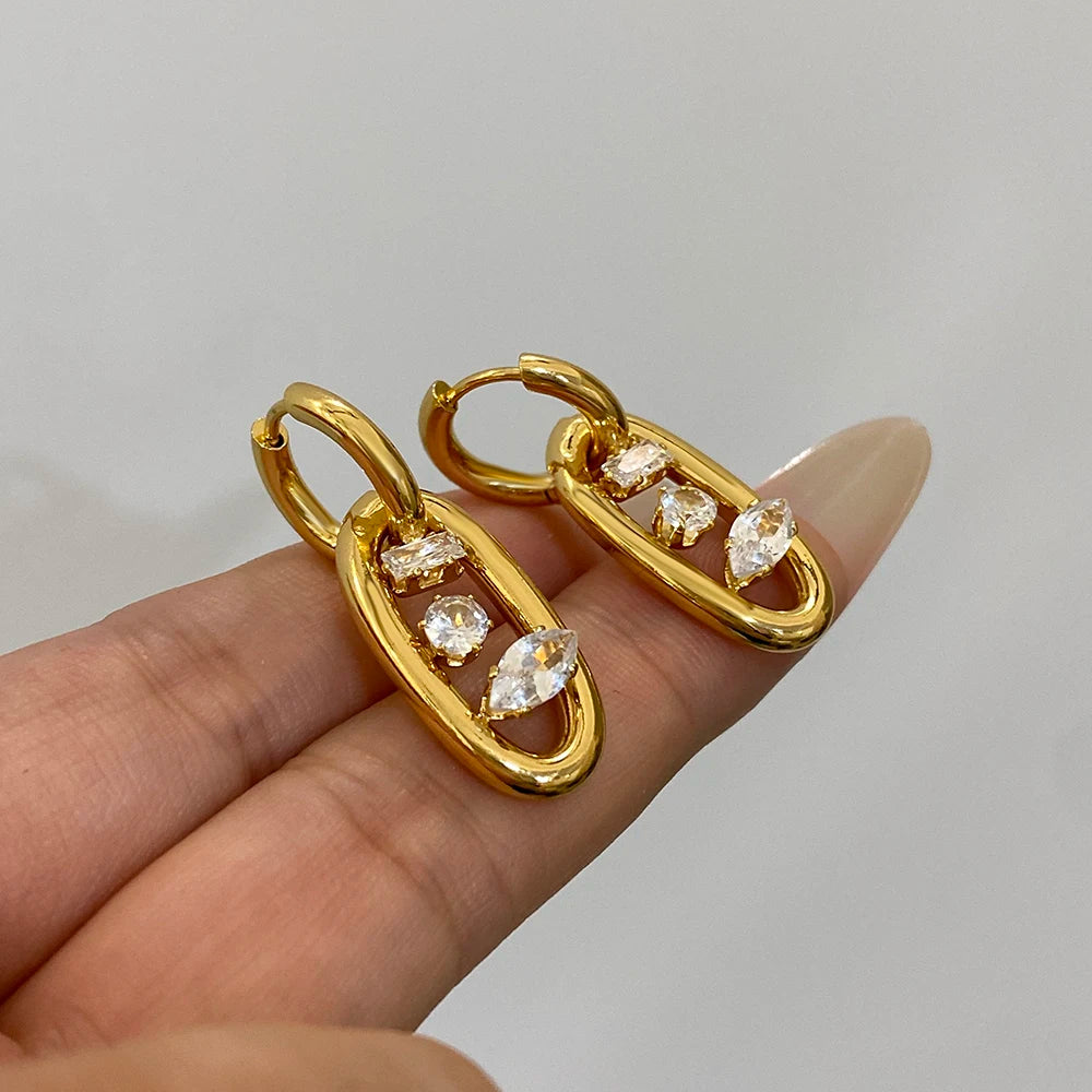 Gold-plated hoop earrings with dangling zircon stones, close-up