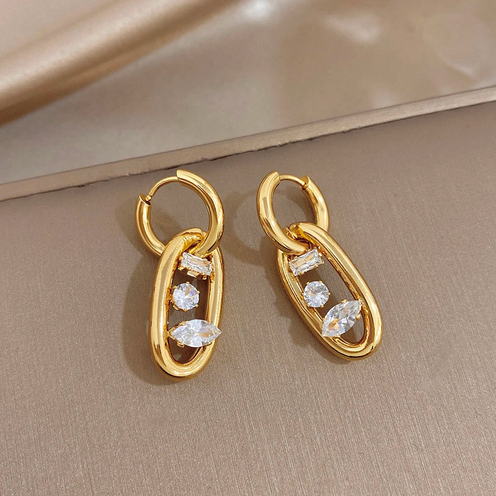 Gold hoop earrings with clear crystal cluster accents inside oval drop frames