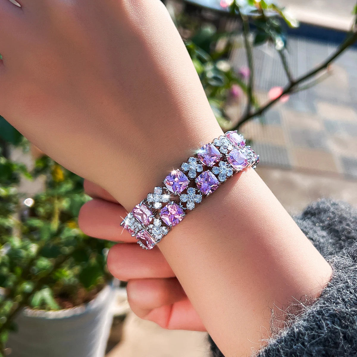 Purple and clear cubic zirconia flower tennis bracelet worn on the wrist
