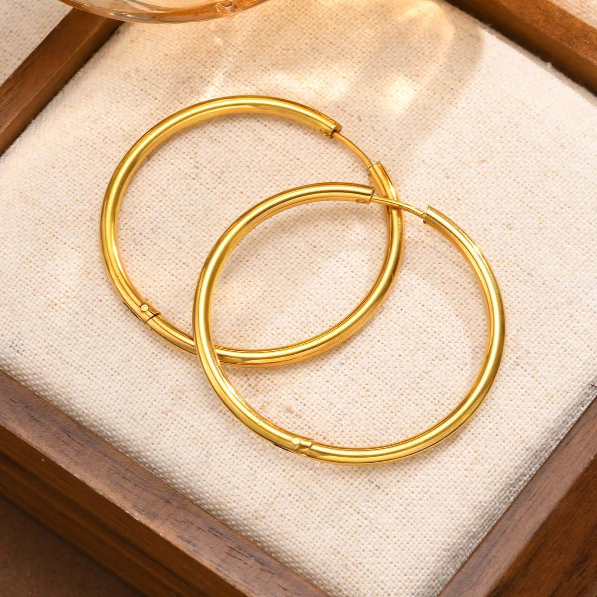 Pair of large, slim gold hoop earrings with hinged closures.