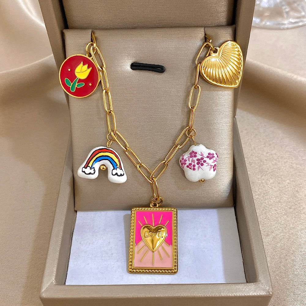 Gold chain necklace with colorful cloud and leaf charms and pink sun heart pendant