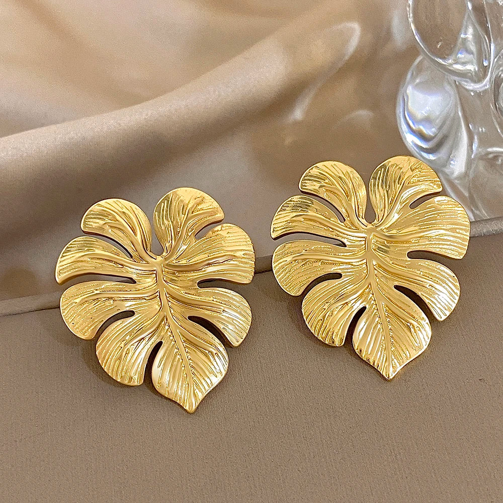 Gold leaf-shaped stud earrings with textured veins and cutout details