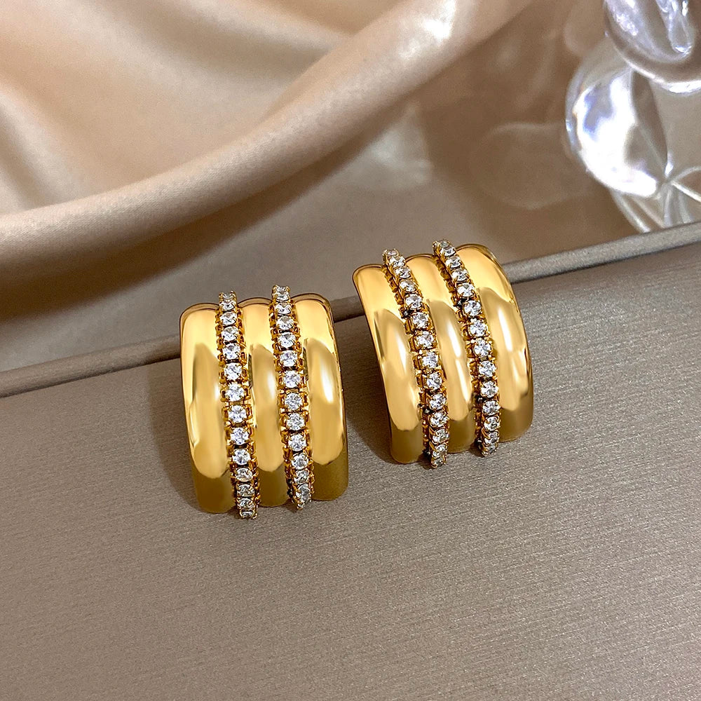 Gold-tone stud earrings with two rows of clear rhinestones and ridged polished bands