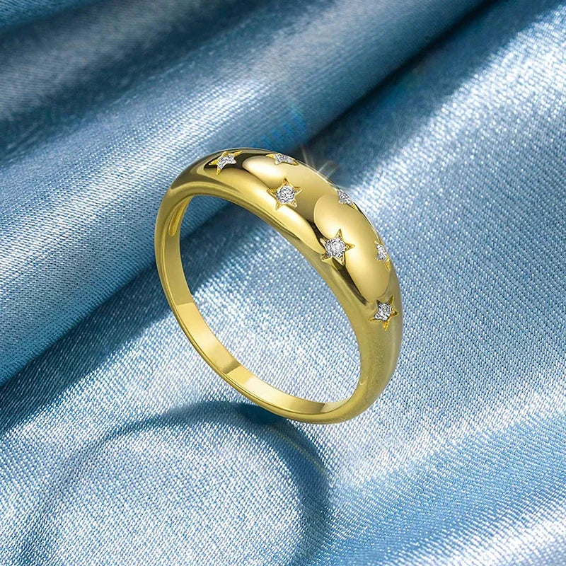 Gold-tone wedding band with star inlays and round sparkle stones, angled view