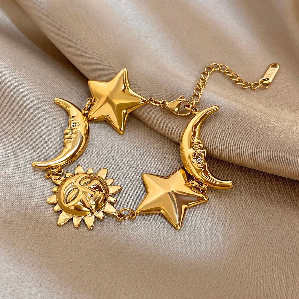 Gold-tone charm bracelet close-up with crescent moons, star charms, and sun centerpiece links