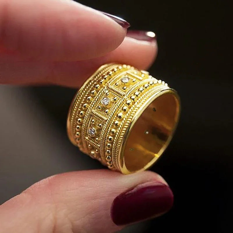 Wide gold-tone ring with raised beadwork, geometric panels, and clear stones