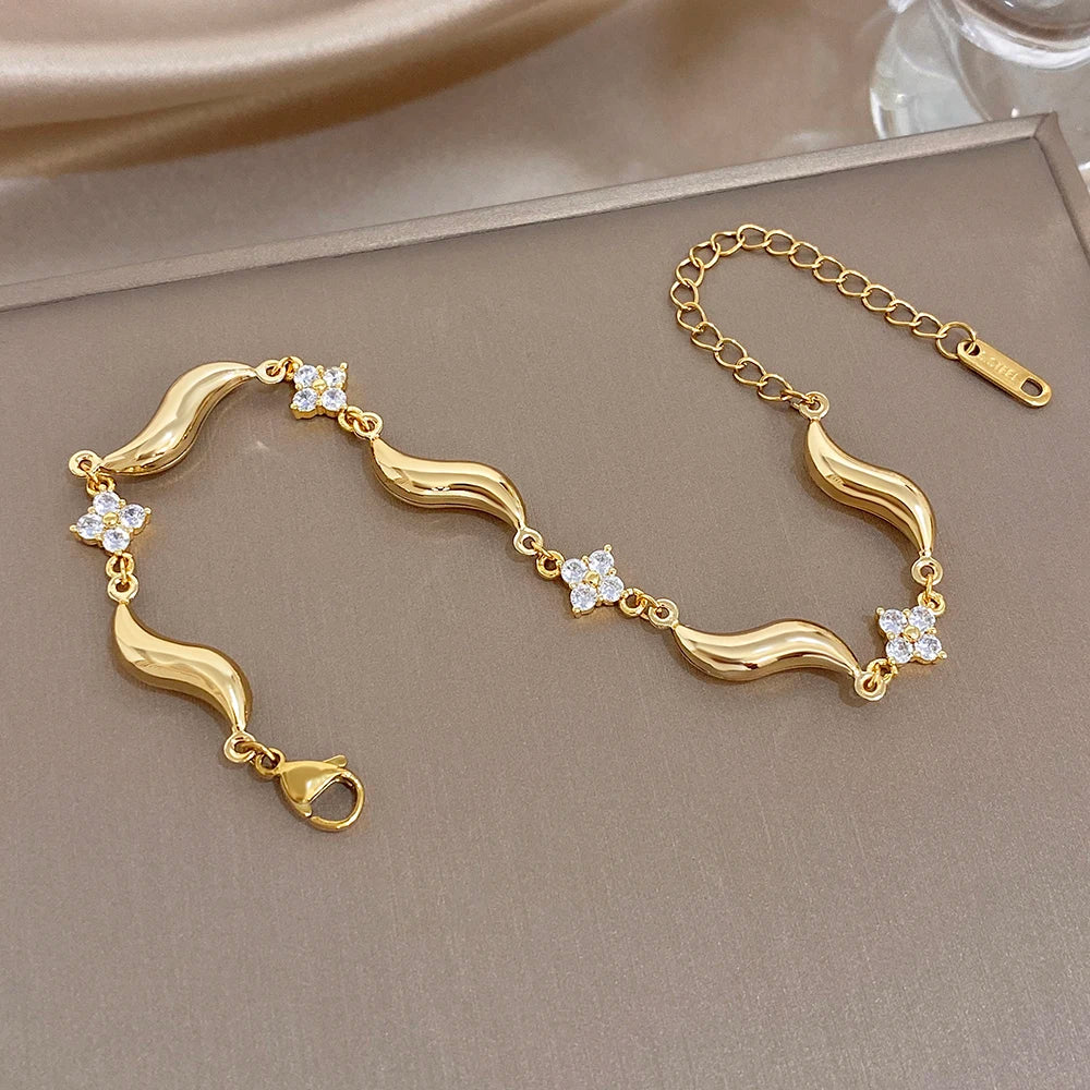 Gold-plated wave bracelet in box with crystal flower stones and clasp detail