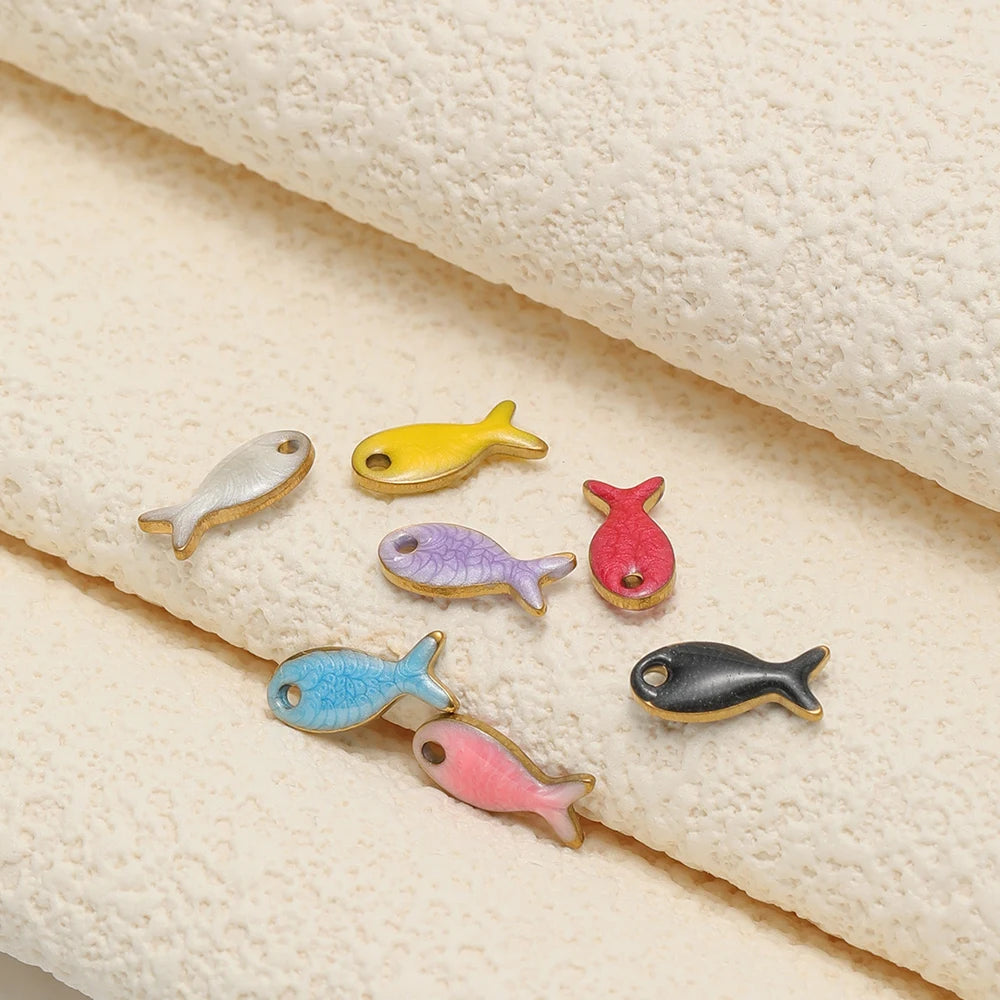 Assorted double-sided fish charms on fabric: yellow, blue, pink, purple, black