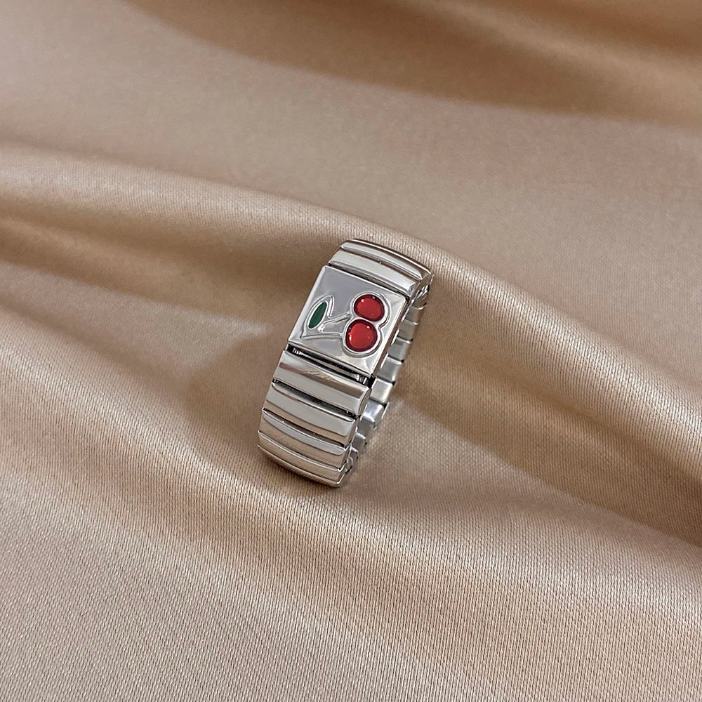Silver adjustable watchband-style finger ring with red cherry enamel and green leaf accents