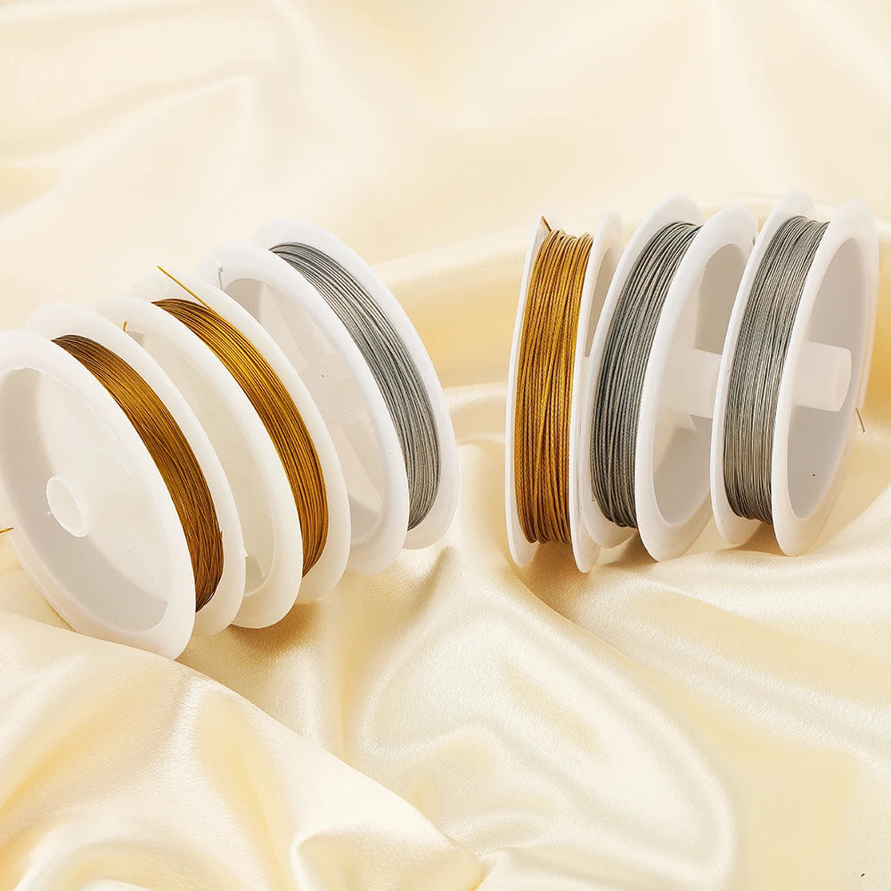 Stainless steel beading wire cords, several gold and steel spools on fabric