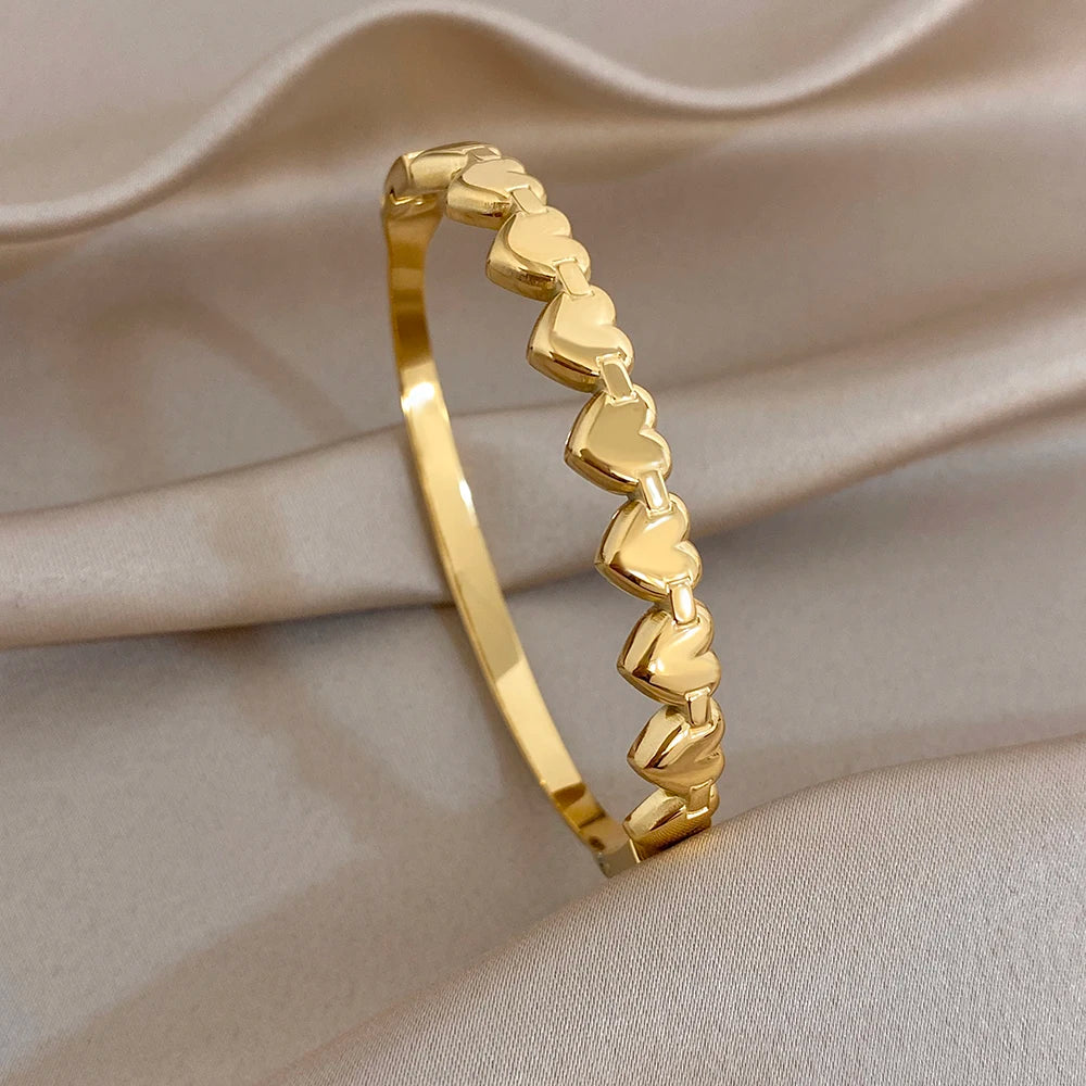 Gold-tone heart-link cuff bangle with raised heart motifs along the bracelet