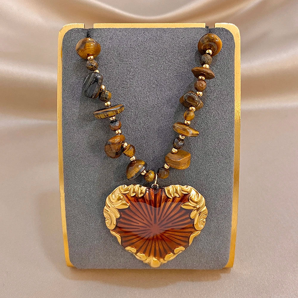 Heart pendant necklace displayed on card with gold chain, brown beads, red sunburst charm