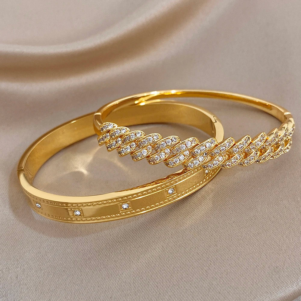 Gold tone bracelet cuffs with clear rhinestone inset bands and curved geometric accents.