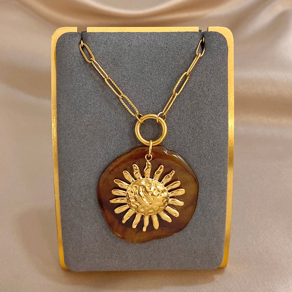 Gold-tone chain pendant necklace with large amber round sun charm and gold sunburst relief