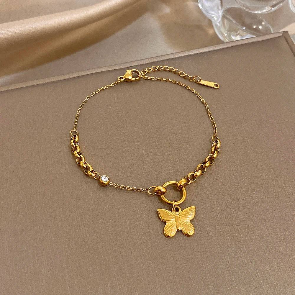 Gold-tone slim chain bracelet with butterfly charm and blue gemstone accents