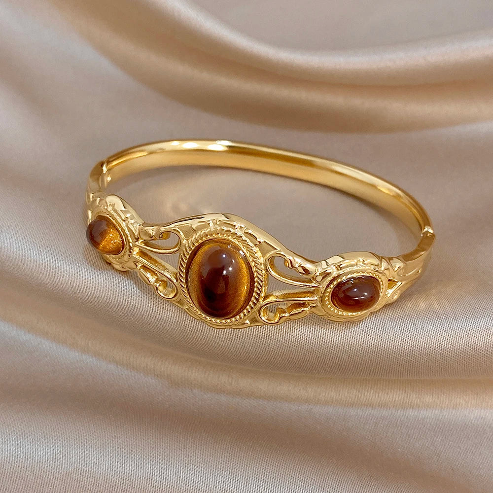 Gold-tone oval center stone cuff bangle with two round tiger-eye side accents