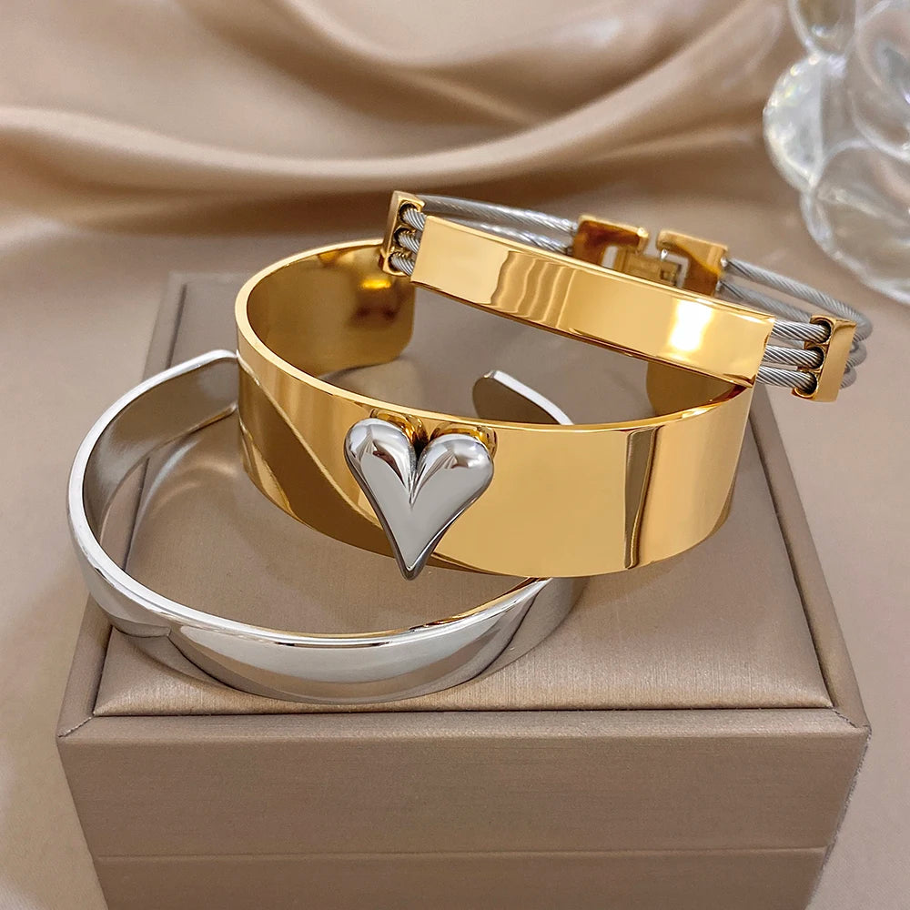 Gold and silver cuff bangles with glossy finish and centered heart charm on gold cuff