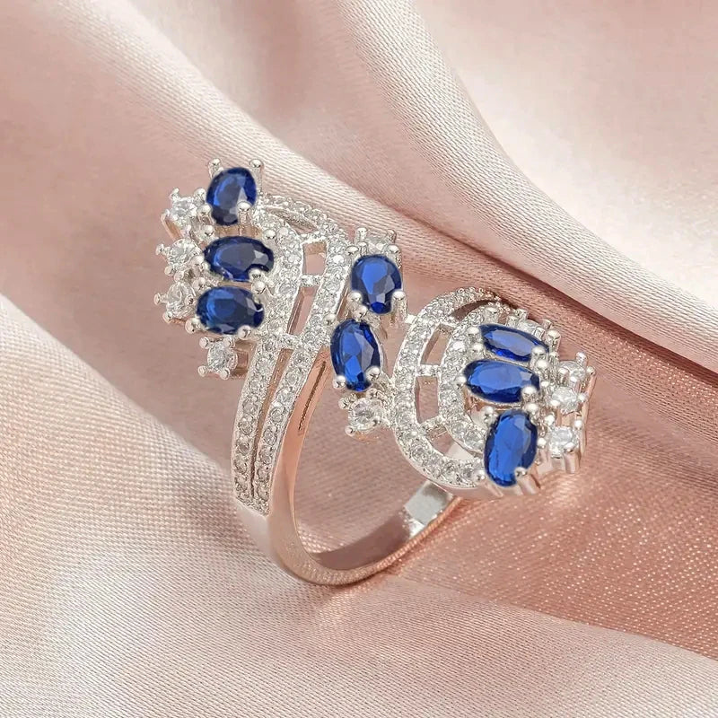 Rose-gold bridal cubic zirconia ring with blue oval stones and openwork curved halos