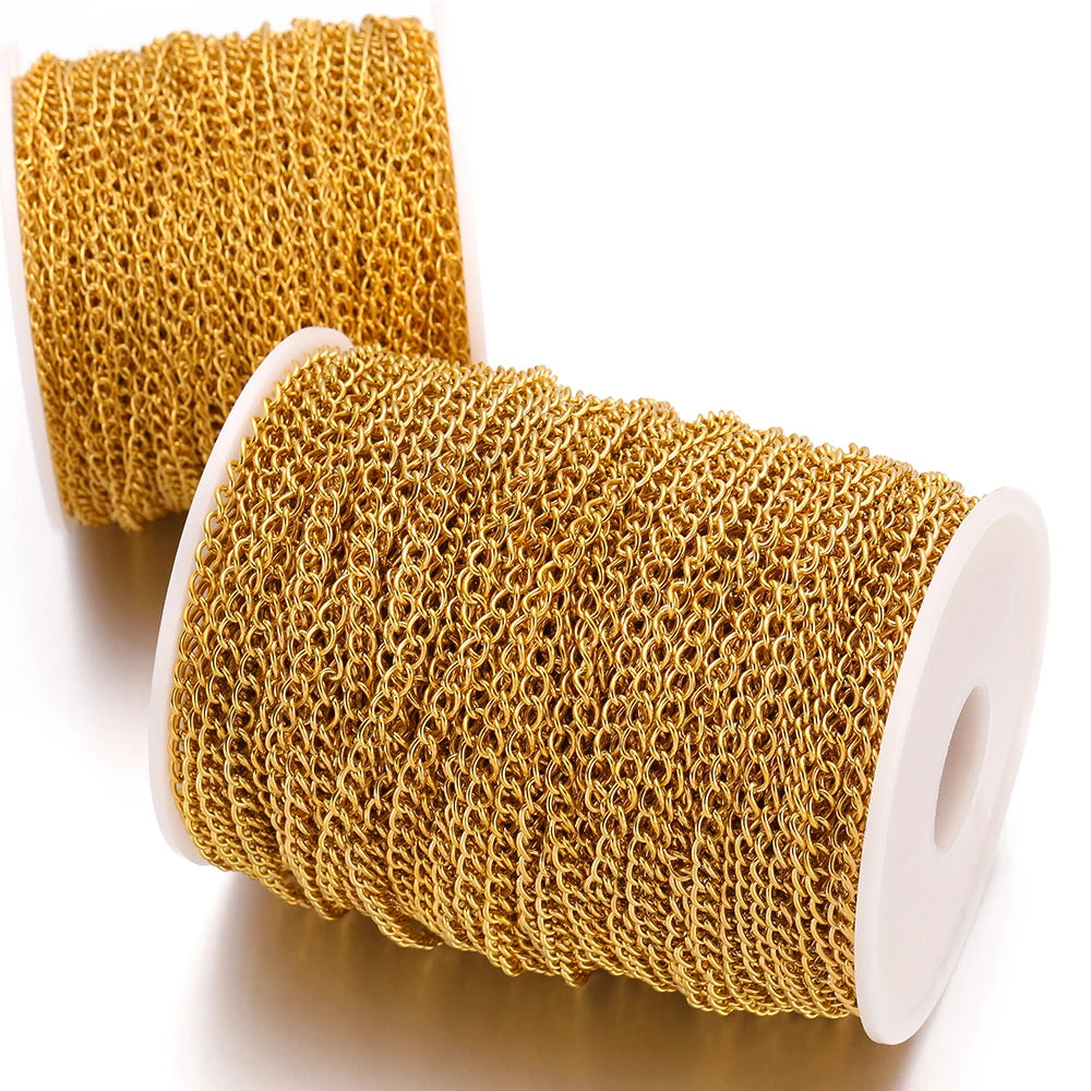 Gold chain extension links on two curled white spools, close-up of coiled mesh weave