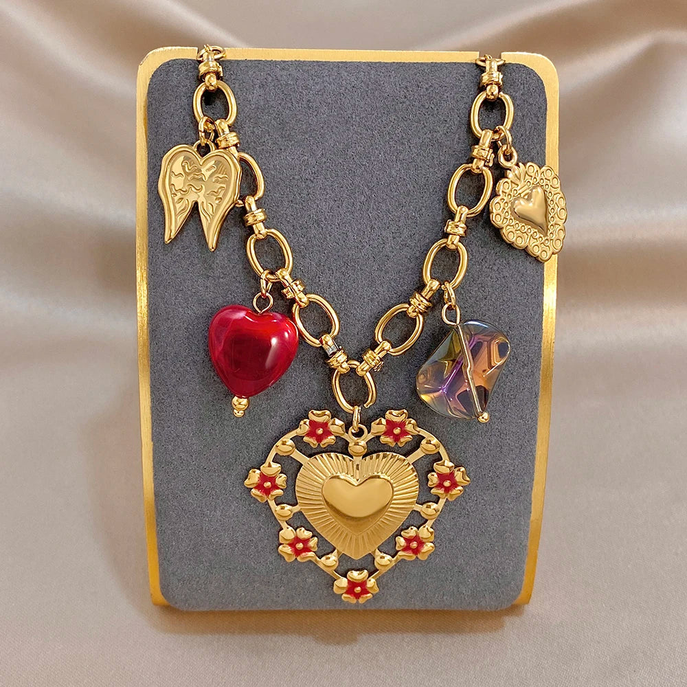 Gold-tone heart charm bracelet with red heart beads, amber beads, wing charm, heart medallion