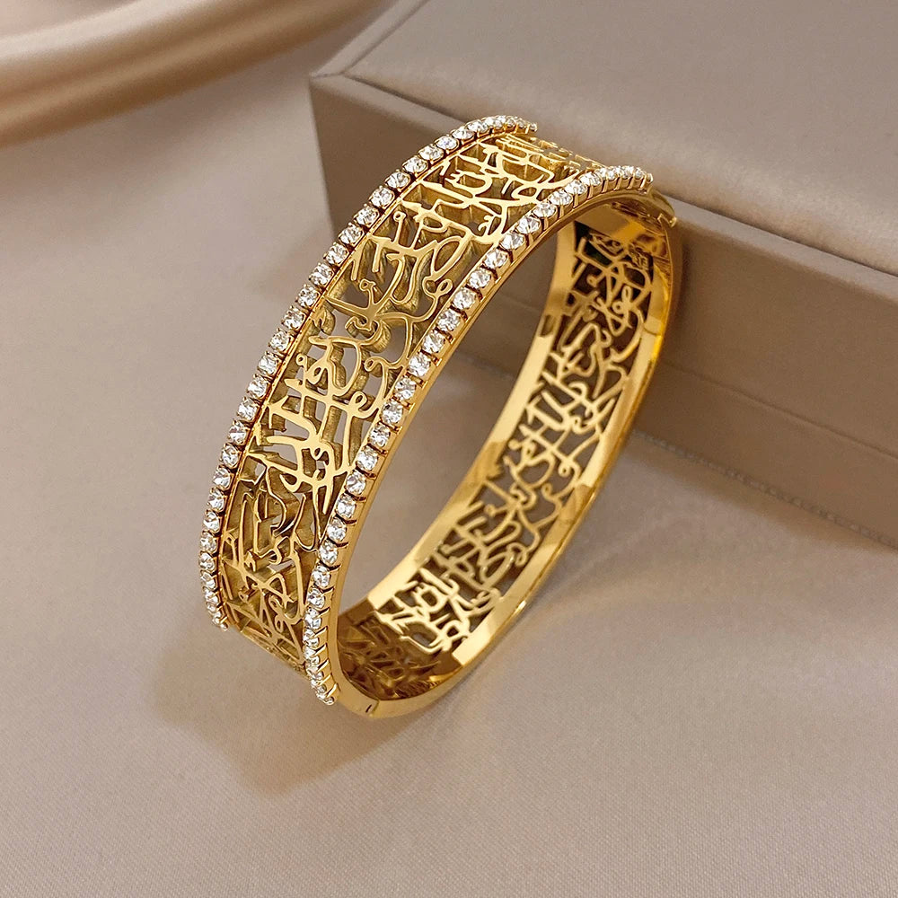 Gold-tone open-front cuff bracelet with hollow geometric engraving and rhinestone edge