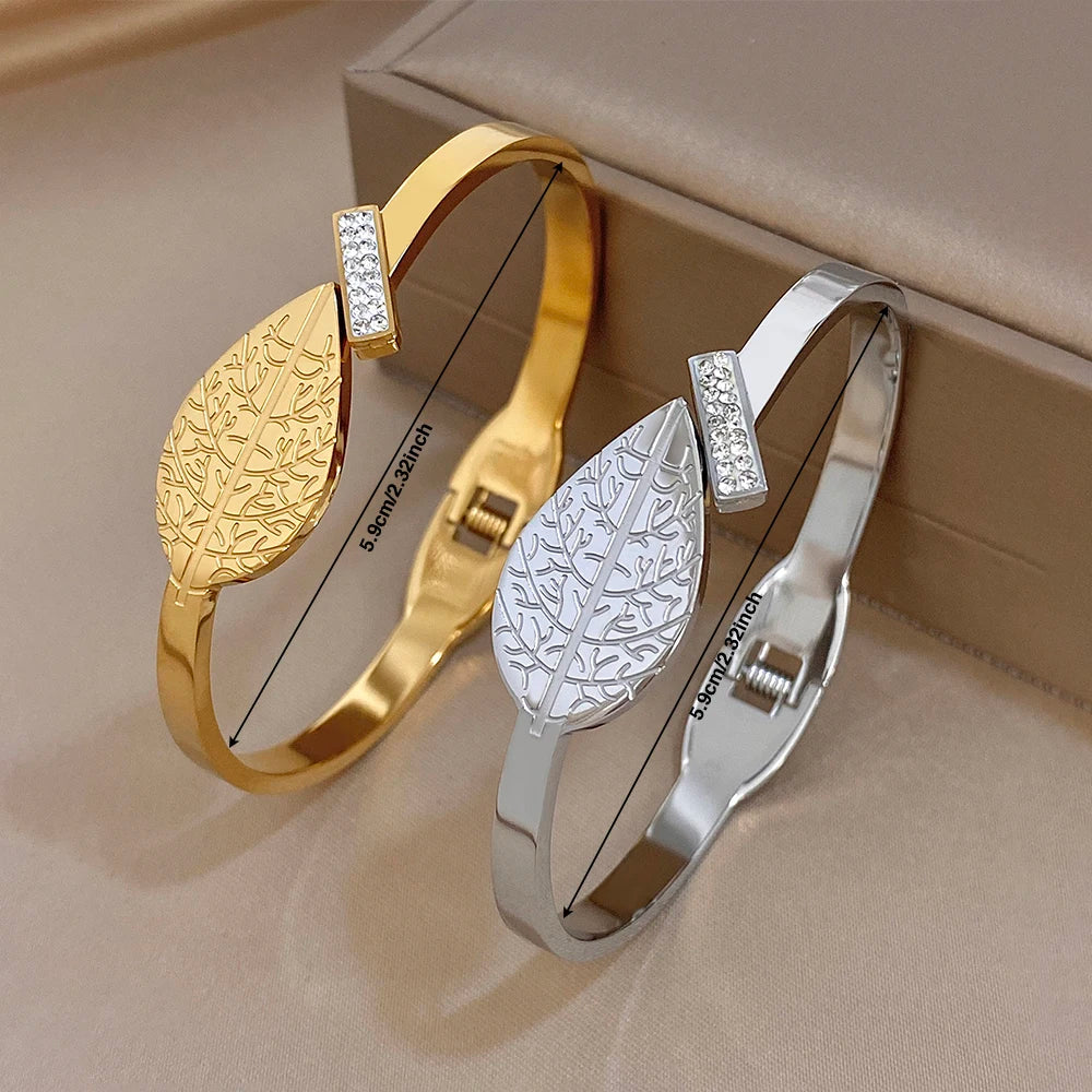 Pair of gold and silver leaf-pattern cuff bangles with rhinestone square accents.