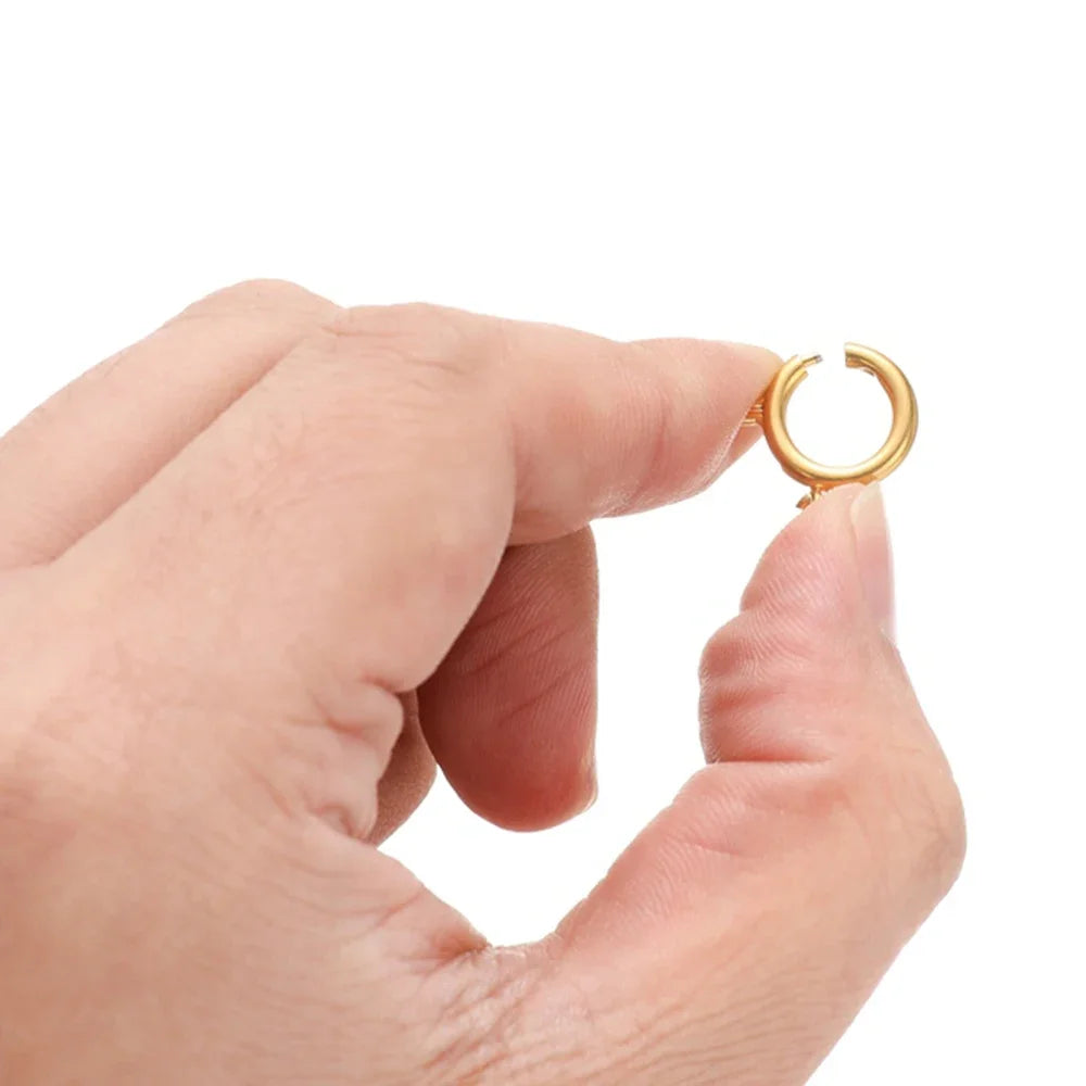 Gold spring clasp round connector held in hand, hook ring closure