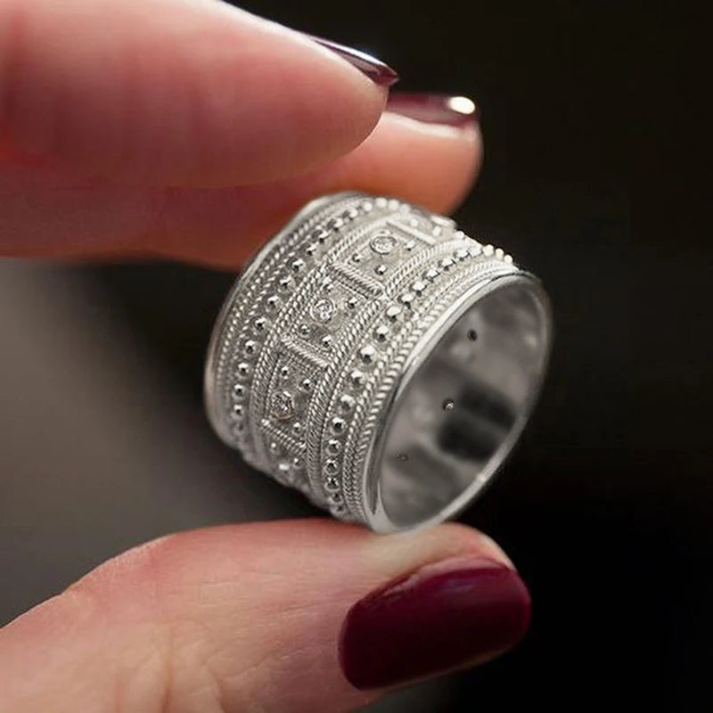 Wide silver-tone ring with raised beadwork, geometric panels, and clear stones