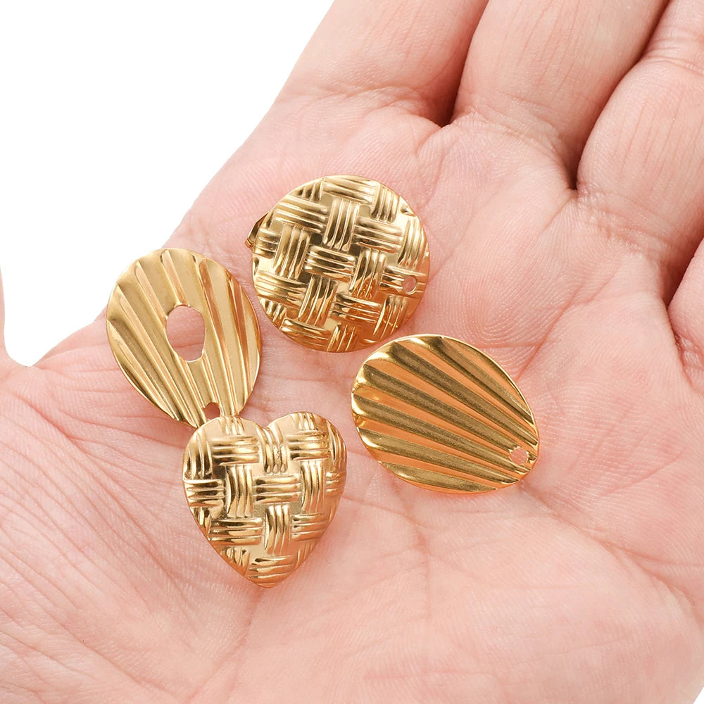 Gold heart-shaped braid earring findings in a hand, textured woven and ribbed surfaces