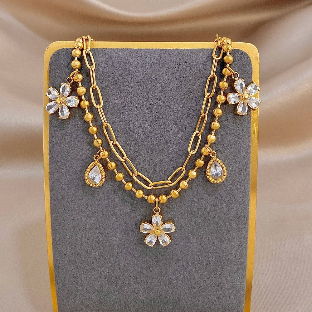 Gold-tone multi-layer chain bracelet with crystal flower and teardrop drop charms
