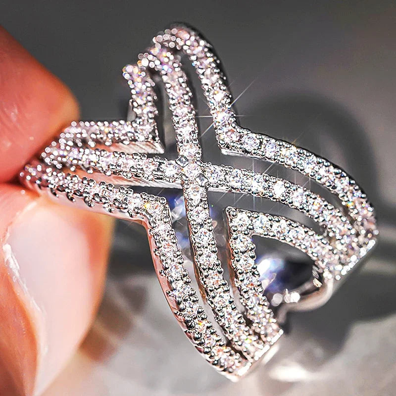 Sparkling rhinestone cross ring on finger, silver-tone openwork design, close-up