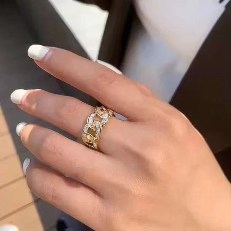 Gold-tone chain-link cubic zirconia ring on finger, sparkling white stones